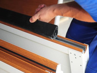 Contractor installing garage door weatherproofing garage door seal. Replace Garage Door Seal.
